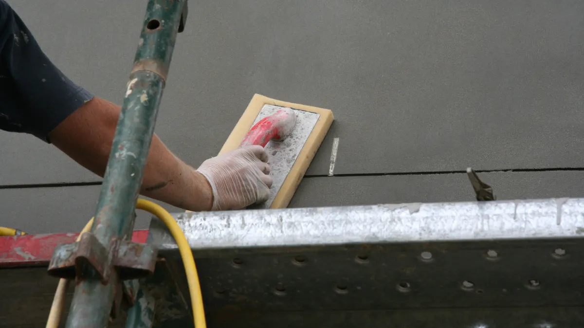 Bricklayer finishing off a brick weep hole in a rendered wall